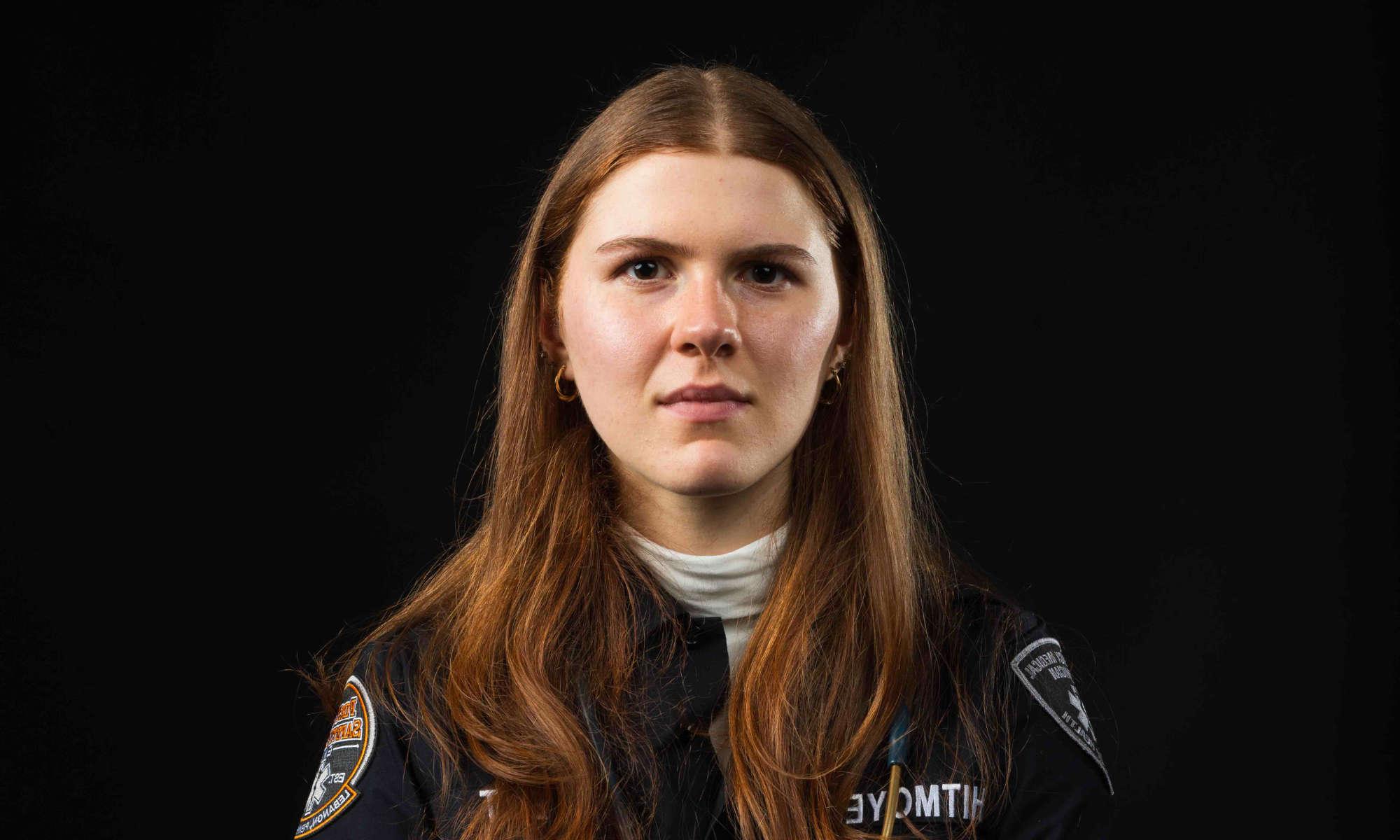 关闭-up horizontal of Rachel Whitmoeyer against a black background in an EMT uniform staring at the camera.